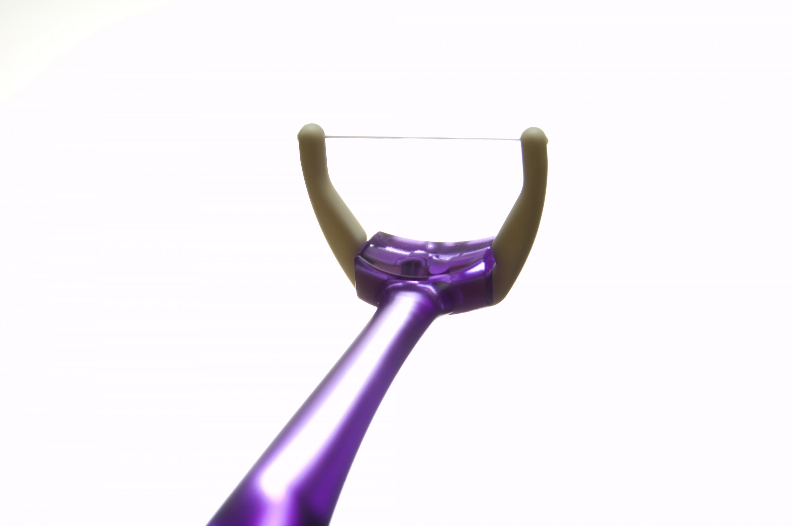 A purple dental floss holder with a thin floss string, positioned against a light background.