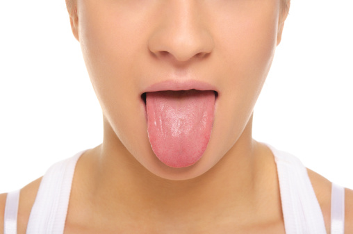 A woman sticking out her tongue, showing her oral health, against a plain white background.